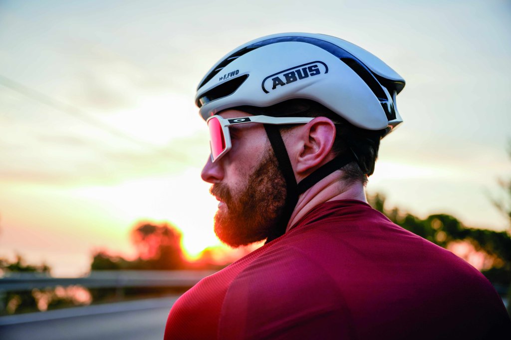 Ein Mann mit weißem Rennradhelm und Sportbrille.