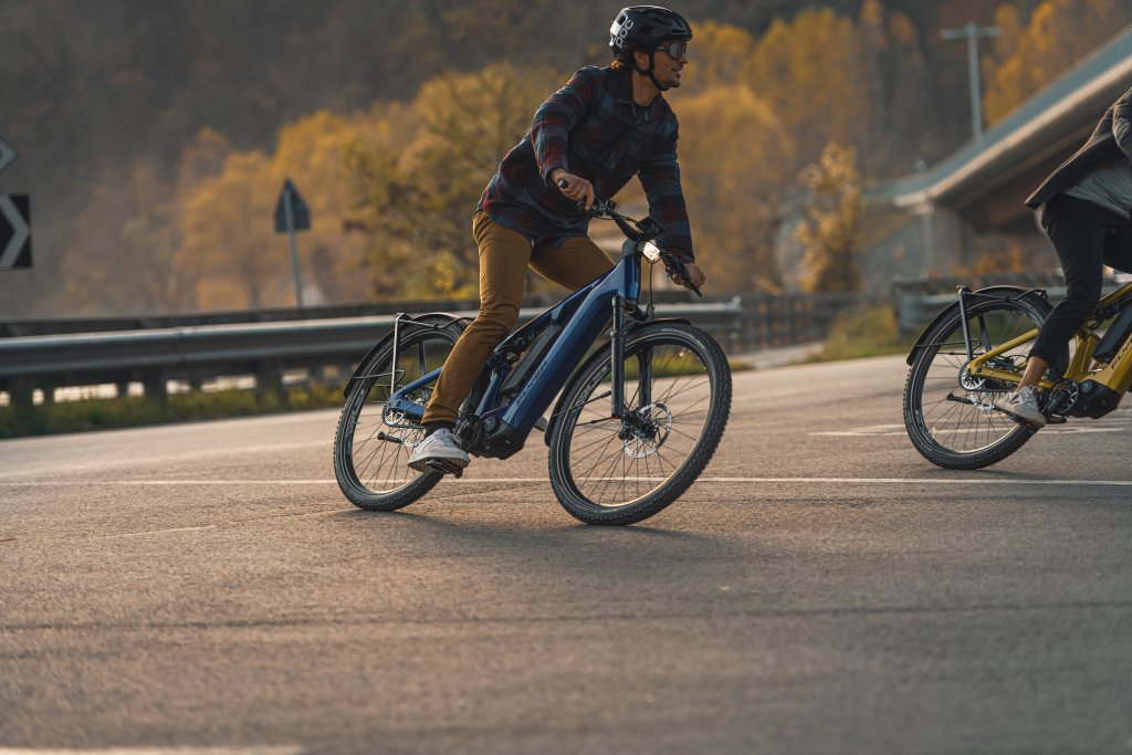 Mann fährt mit Fahrrad auf Landstraße durch eine Kurve.