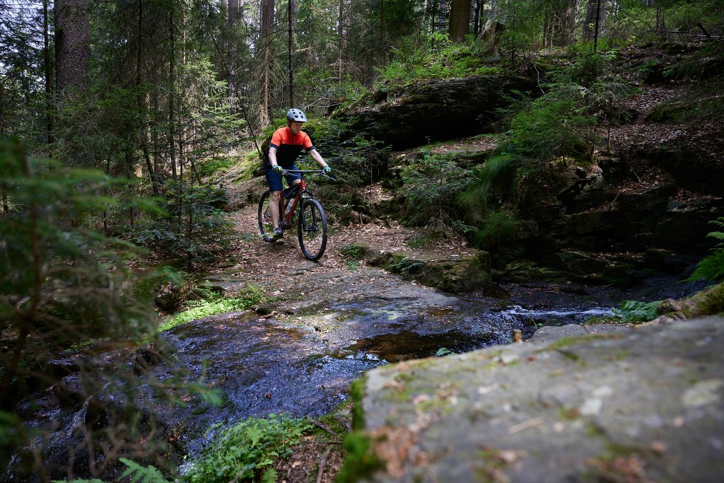 Mountainbiker fährt durch Bach.