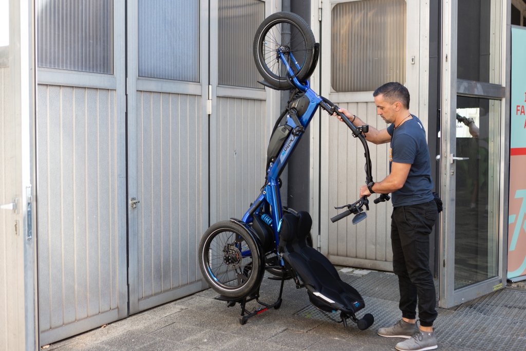 Ein Mann parkt das Sesselrad \\\\\\\"Delta tx\\\\\\\" von HP Velotechnik aufrecht an einer Wand.