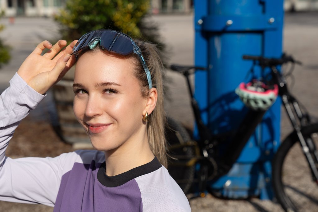 Frau pausiert bei Fahrradtour in der Sonne mit Sonnenbrille.