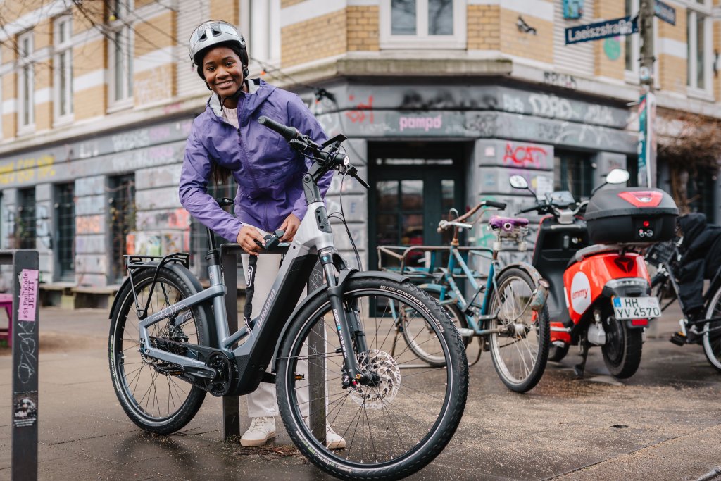 Frau schließt E-Bike an Anlehnparker mit Fahrradschloss an.