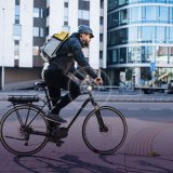 Eine Person fährt auf einem E-Bike durch eine Stadt.